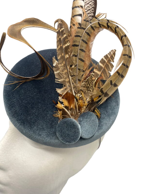 Blue/grey velvet headpiece with a spray of brown feathers.